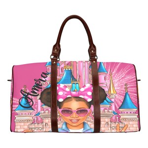 May include: Pink travel bag featuring a cartoon girl with sunglasses and a polka dot bow, in front of a castle. The bag has brown leather handles and the name "Amora" in cursive. The background includes fireworks.