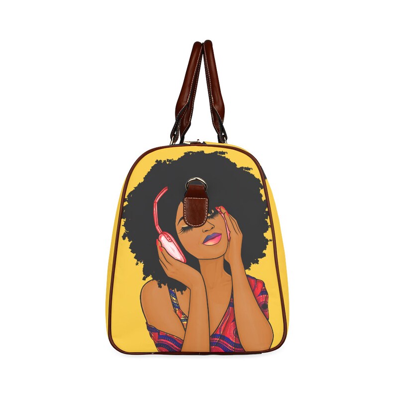 May include: Yellow duffel bag featuring a graphic of a woman with an afro wearing headphones. The bag has brown leather handles and trim. The woman in the graphic is wearing a red and blue patterned top.