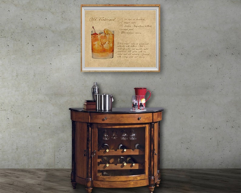 May include: A wooden bar cart with a glass door revealing a wine rack and glasses. The cart has a black marble top and a framed print of an Old Fashioned cocktail recipe.