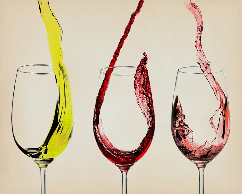May include: Three wine glasses with different colored liquids pouring into them. The glass on the left has a yellow liquid, the middle glass has a red liquid, and the glass on the right has a pink liquid.