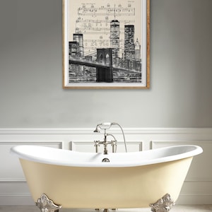 May include: A framed print of a black and white photograph of the New York City skyline with the Brooklyn Bridge in the foreground. The image is superimposed on a sheet of music with the title "New York State of Mind" by Billy Joel.