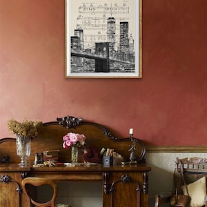 May include: A black and white print of the New York City skyline with the Brooklyn Bridge and the World Trade Center. The print is framed in a white frame and has the text "New York State of Mind" at the top.