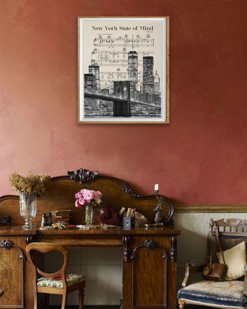 May include: A black and white print of the New York City skyline with the Brooklyn Bridge and the World Trade Center. The print is framed in a white frame and has the text "New York State of Mind" at the top.