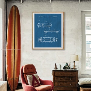 Pu&ograve; includere: Una stampa di brevetto di skateboard vintage blu e bianca in una cornice di legno appesa a un muro di mattoni bianchi. La stampa &egrave; circondata da un ambiente da salotto con una poltrona rossa, una cassettiera in legno e una tavola da surf.