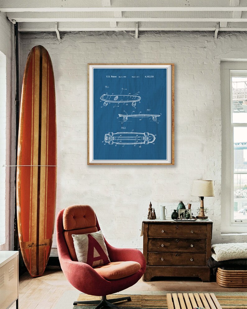Pu&ograve; includere: Una stampa di brevetto di skateboard vintage blu e bianca in una cornice di legno appesa a un muro di mattoni bianchi. La stampa &egrave; circondata da un ambiente da salotto con una poltrona rossa, una cassettiera in legno e una tavola da surf.