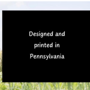 May include: Black and white text on a black background against a blurred background of green grass and a blue sky. The text reads "Designed and printed in Pennsylvania."