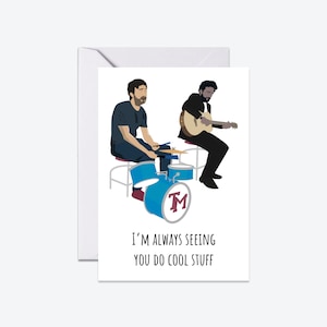 May include: A greeting card featuring a cartoon illustration of two people playing music. One person is playing drums and the other is playing guitar. The text on the card reads "I'm always seeing you do cool stuff."