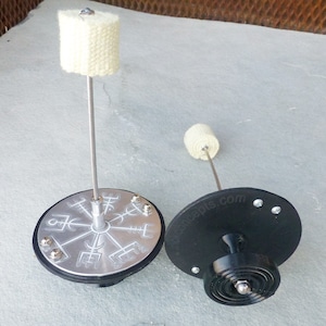 May include: Two fire spinning poi with black bases and silver tops. The top of the poi has a circular design with symbols. One poi has a white wick and the other has a black wick. The base of the poi has the text "firetoys.com".