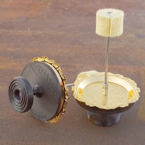 May include: Two gold-colored decorative stands with black bases. The stand on the left has a black knob and the text "Trick or Treat" on the base. The stand on the right has a white wick on a metal rod.