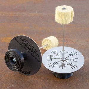 May include: Two fire spinning tools with a black base and a silver base. The silver base has a compass design with a black center. The black base has the text "Trick Concepts" and "Because Everything Looks Better on Fire!" printed on it. Both bases have a metal rod with a white fire wick attached to it.