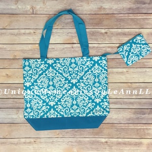 May include: A turquoise tote bag with a white damask pattern. The bag has a zipper closure and comes with a matching turquoise zippered pouch. The bag is made of a durable fabric and is perfect for carrying everyday essentials.