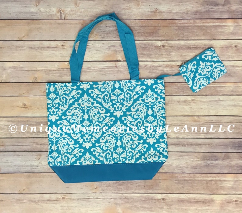 May include: A turquoise tote bag with a white damask pattern. The bag has a zipper closure and comes with a matching turquoise zippered pouch. The bag is made of a durable fabric and is perfect for carrying everyday essentials.