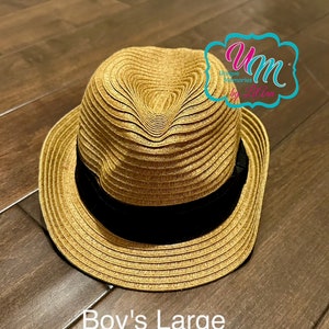 May include: A straw hat in a light brown color with a black band around the crown. The hat is labeled "Boy's Large".