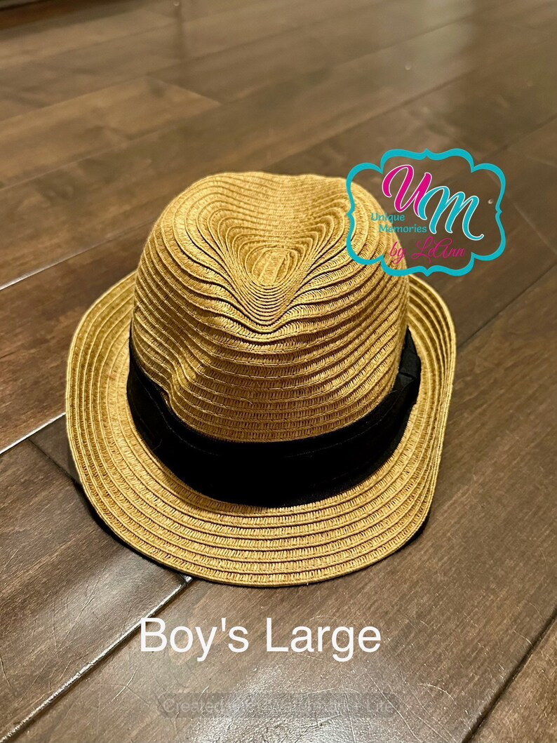 May include: A straw hat in a light brown color with a black band around the crown. The hat is labeled "Boy's Large".