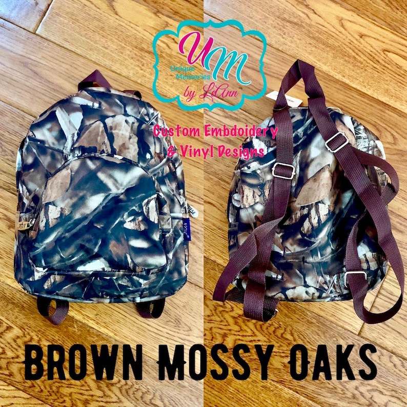 May include: A small brown and green camouflage backpack with brown straps. The backpack has a large pocket on the front and a smaller pocket on the side. The text "BROWN MOSSY OAKS" is printed below the backpack.