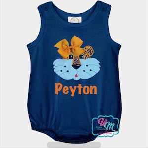 May include: Navy blue baby romper with a tiger face design. The tiger face has a light blue muzzle, orange bow, and the name "Peyton" in orange letters. The romper has snap closures on the shoulders.