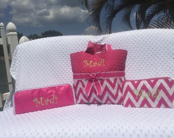 May include: Pink and white chevron patterned tote bag, cosmetic bag, and pencil case with the name "Madi" embroidered in gold on each piece.
