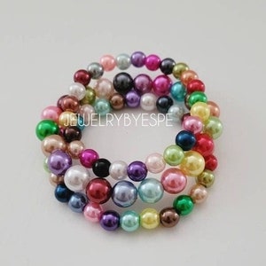 May include: Multicolored pearl bracelet with a variety of colors, including pink, green, blue, and purple.