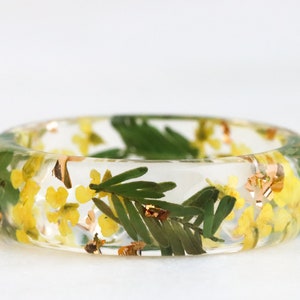 Faceted resin ring adorned with real pressed Yellow Queen Anne's Lace Flowers and Green Mimosa Leaves. Well-polished, lightweight, comfortable, and shiny.