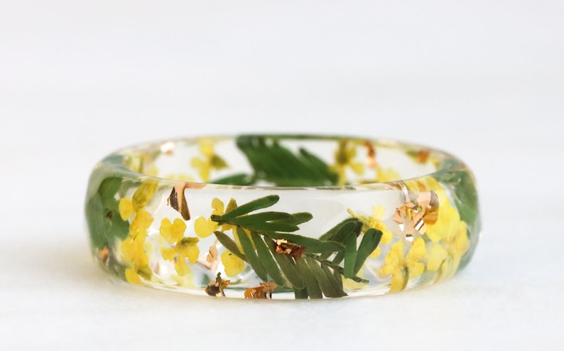 Faceted resin ring adorned with real pressed Yellow Queen Anne's Lace Flowers and Green Mimosa Leaves. Well-polished, lightweight, comfortable, and shiny.