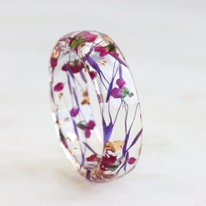 Harsring met geperste roze en paarse bloemen en zilver/goud/kopervlokken, natuursieraden, gefacetteerde ring