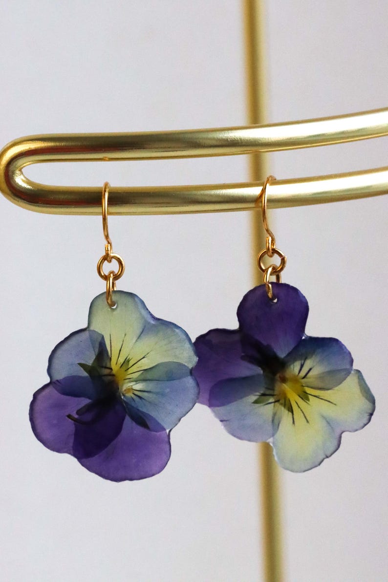 Pressed pansy flower earrings hanging on gold hooks