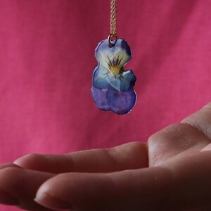 Pressed pansy flower necklace pendant in hand