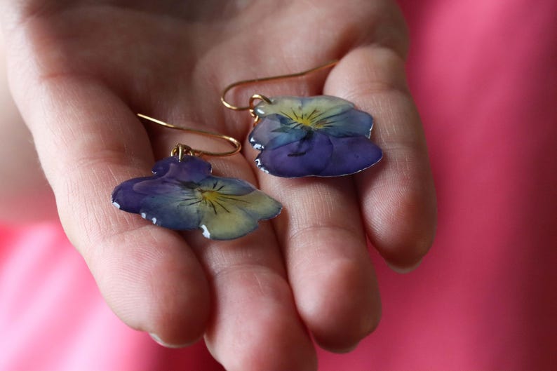 Real pansy flower earrings held in hand showing natural petal detail
