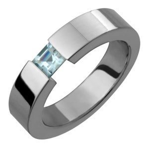 May include: A silver ring with a light blue gemstone set in a unique, modern design.