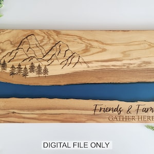 May include: A wooden serving board with a blue epoxy river design and a mountain scene engraved on the top. The text "Friends & Family Gather Here" is engraved below the river.