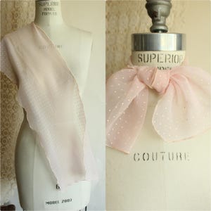 May include: A pale pink scarf with white polka dots is displayed on a mannequin. The scarf's edge is scalloped, and the fabric is sheer. The mannequin is labelled "Superior Model Form Co."