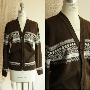 May include: A brown cardigan sweater with a white geometric pattern across the chest and sleeves. The sweater has a V-neck and button closure. The sweater is displayed on a mannequin.