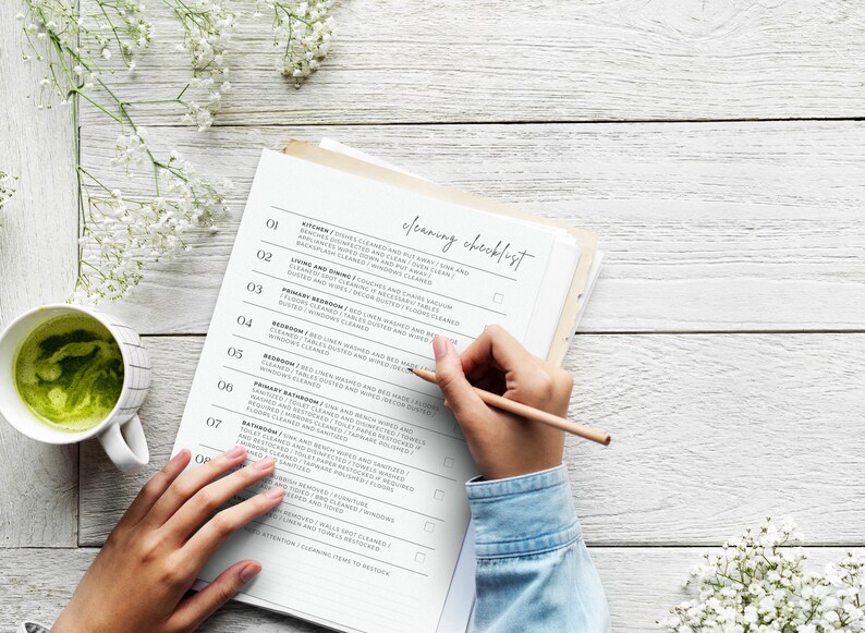 K&ouml;nnte beinhalten: Eine Reinigungscheckliste mit einer Hand, die einen Bleistift h&auml;lt und Punkte auf der Liste abhakt. Die Checkliste enth&auml;lt Aufgaben f&uuml;r K&uuml;che, Wohn- und Esszimmer, Hauptschlafzimmer, Schlafzimmer, zweites Badezimmer, Badezimmer und Waschk&uuml;che.