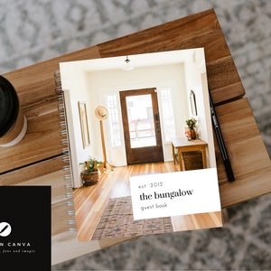 May include: A white guest book with a spiral binding. The cover features a photo of a home's entryway with a wooden door, a rug, and a plant. The text on the cover reads "est. 2012 the bungalow guest book".