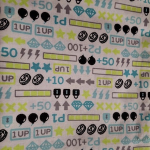 May include: White fabric featuring a repeating pattern of video game icons. The design includes pixelated coins, bombs, diamonds, lightning bolts, arrows, stars, and the text "1UP", "+10", "+50", and "P1".