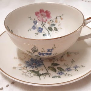 Bavarian, German fine porcelain teacup and saucer with eggshell off white colour and floral clusters.  pink blue off white flowers