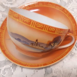 Discounted handpainted fine Japanese porcelain cup and saucer handpainted countryside scenery, in autumn colours, orange tea cup and saucer