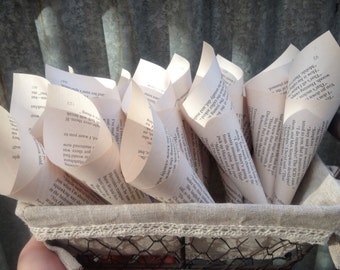May include: A basket filled with paper cones made from book pages. The cones are filled with small pieces of paper, and the basket is lined with a beige fabric with lace trim.