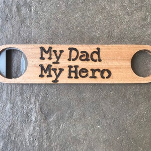 May include: Wooden bottle opener with a cutout for opening bottles and the text "My Dad My Hero" engraved on the surface.