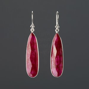 Könnte beinhalten: Ein Paar silberne Ohrhänger mit einem tropfenförmigen Rubin-Edelstein. Die Ohrringe haben ein schlichtes Design und sind perfekt für den Alltag.