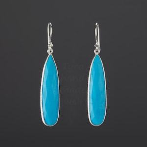 May include: A pair of silver dangle earrings with turquoise teardrop-shaped stones.