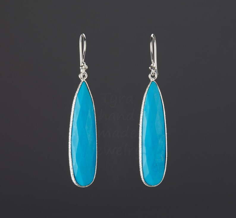 May include: A pair of silver dangle earrings with turquoise teardrop-shaped stones.