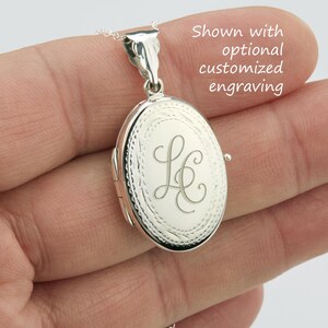 May include: Oval silver locket with an engraved initial design. The locket is suspended from a delicate chain. The text in the image says "Shown with optional customized engraving."