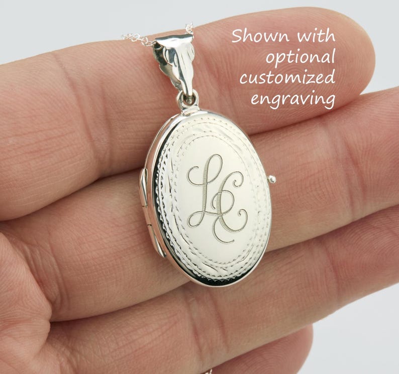 May include: Oval silver locket with an engraved initial design. The locket is suspended from a delicate chain. The text in the image says "Shown with optional customized engraving."