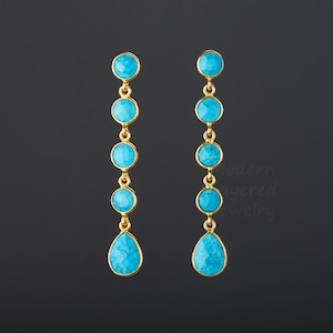 May include: Gold earrings with a turquoise teardrop and round stones hanging from a gold chain.