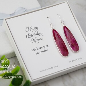 以下が含まれることがあります： 白いギフトボックスには、「ハッピーバースデー、ママ！愛してるよ！」と書かれたカードが入っています。ボックスには、ピンクの宝石の雫が付いたシルバーのドロップイヤリングのペアが入っています。カードのメッセージはカスタマイズできます。アメリカ製です。