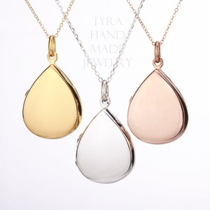 May include: Three teardrop-shaped locket necklaces in gold, silver, and rose gold. The lockets are hanging from delicate chains.