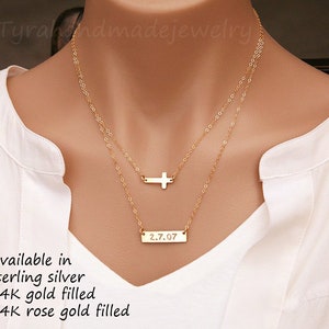 May include: Gold layered necklace with a small cross charm and a bar pendant engraved with the date "2.7.07". Available in sterling silver, 14k gold filled, and 14k rose gold filled.