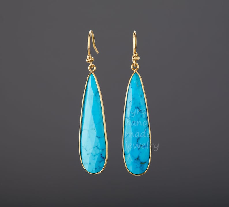 May include: A pair of gold dangle earrings with turquoise teardrop-shaped stones.