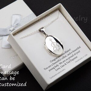 May include: A silver locket necklace with a cello engraving, presented in a white gift box with a silver ribbon. The box contains a personalized message. The locket is on a delicate chain.